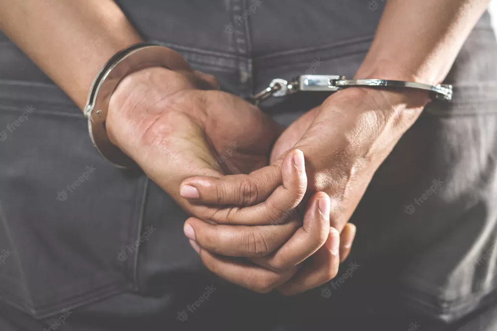 prisionero-pie-esposado-manos-detras-espalda_109549-66
