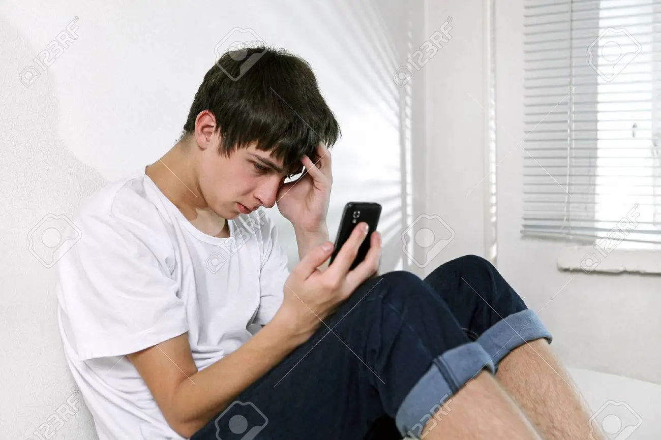 23198688-triste-hombre-joven-con-teléfono-celular-sentado-en-la-cama